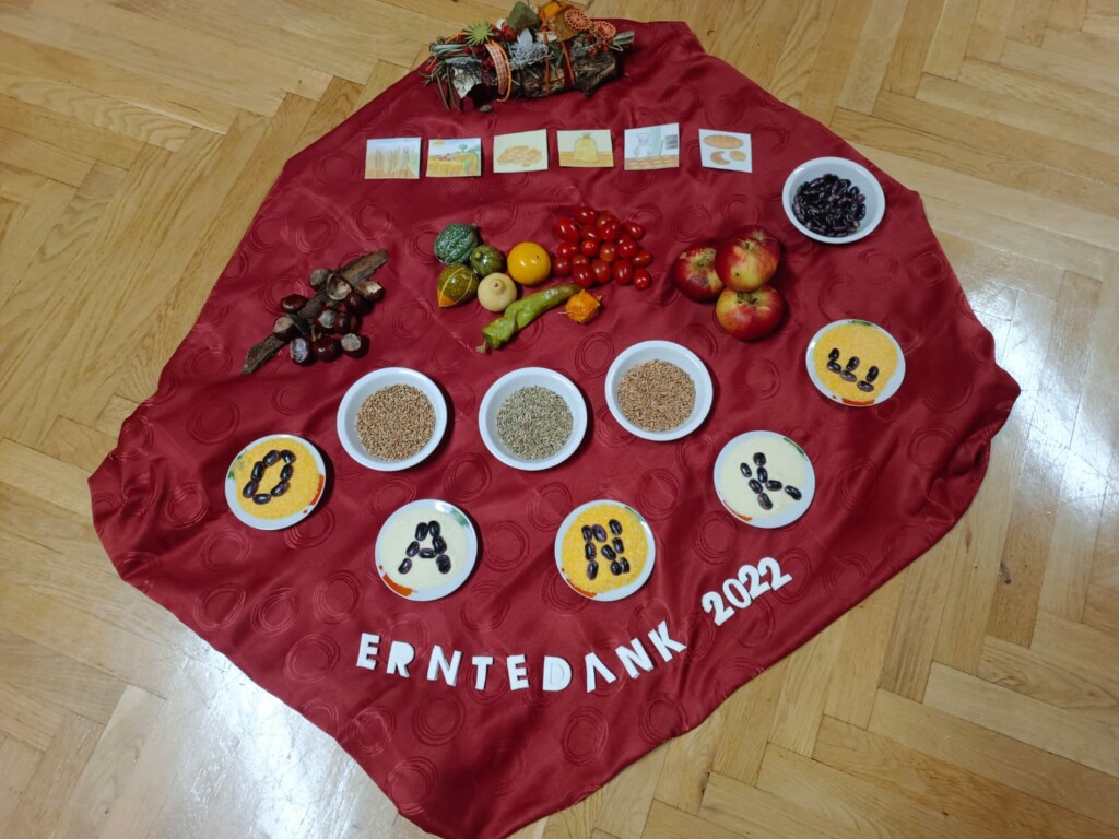 Eine rote Decke mit verschiedenen saisonalen Produkten. Das Wort DANKE und ERNTEDANK 2022 sind hervorgehoben.